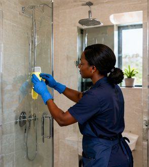 A cleaner scrubbing a shower